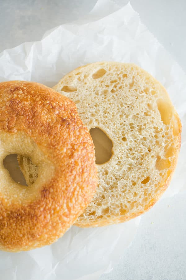 A bagel sliced in half with the top slightly covering the bottom.