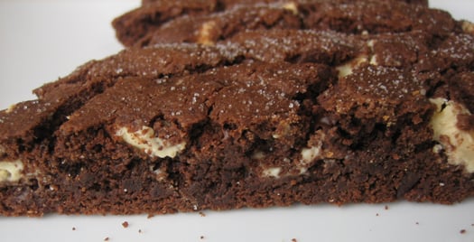 Piece of chocolate biscotti on a white plate.