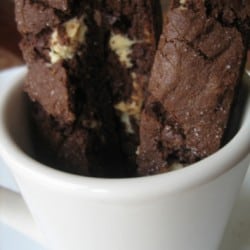 Pieces of chocolate biscotti in a white mug.