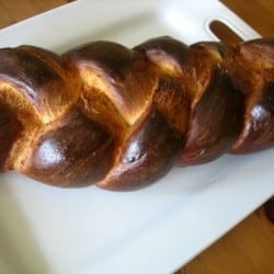 Loaf of challah bread on a white plate.