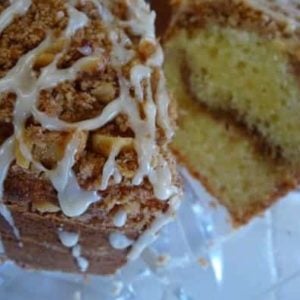 Coffee cake on a glass stand with a slice removed showing the inside.