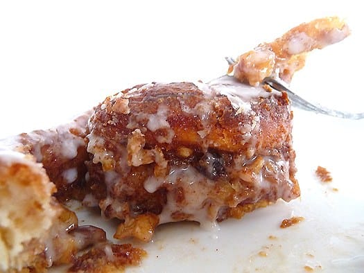 Cream cheese cinnamon roll on a white plate with a fork.