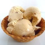 Scoops of butter pecan ice cream in a waffle bowl.