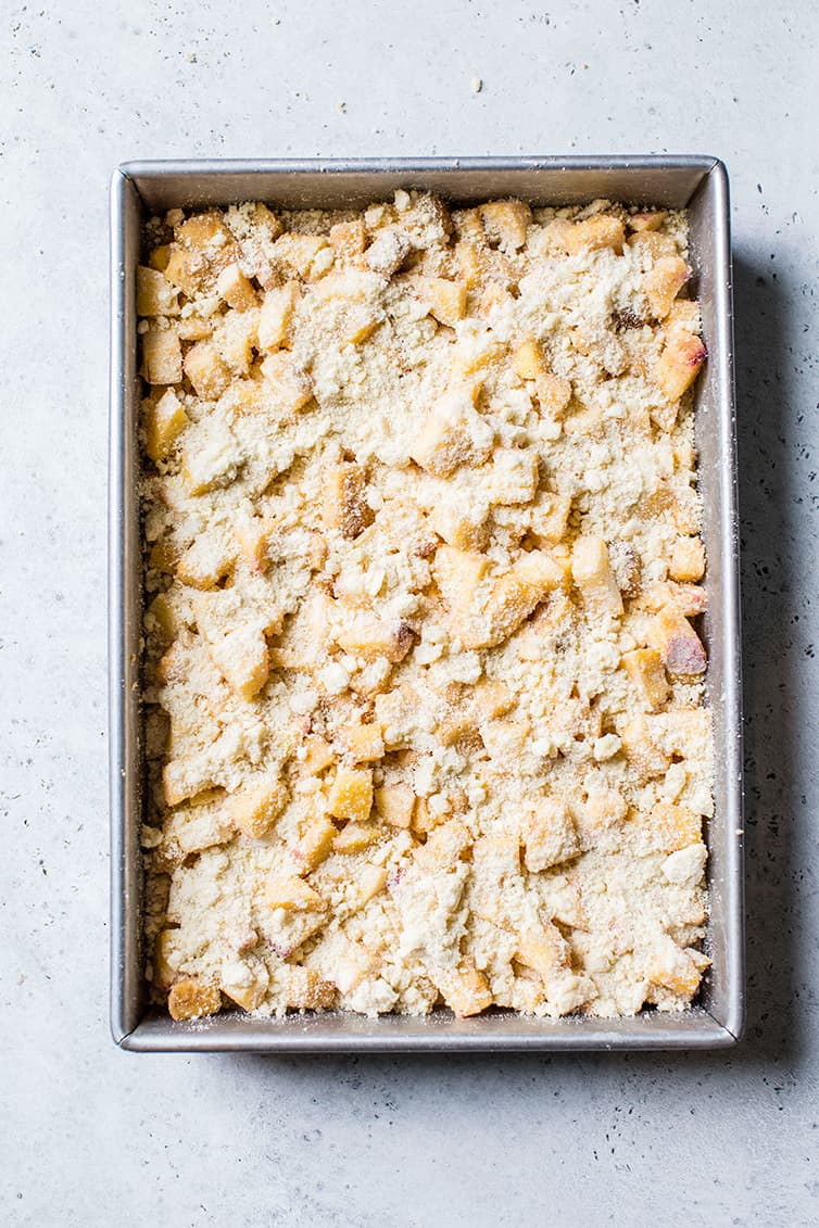 A pan of peach crumb bars prepared before going into the oven.