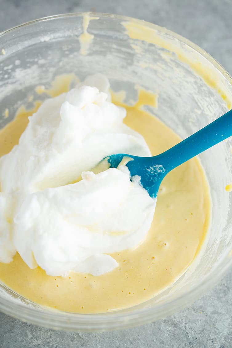 Folding whipped egg whites into cake batter.