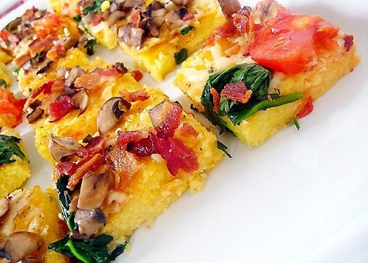 Squares of polenta pizza on a white plate.