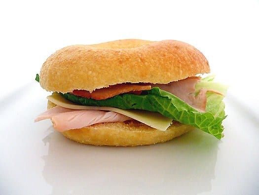 Egg bagel sandwich with lunch meat, slice of cheese, and lettuce.