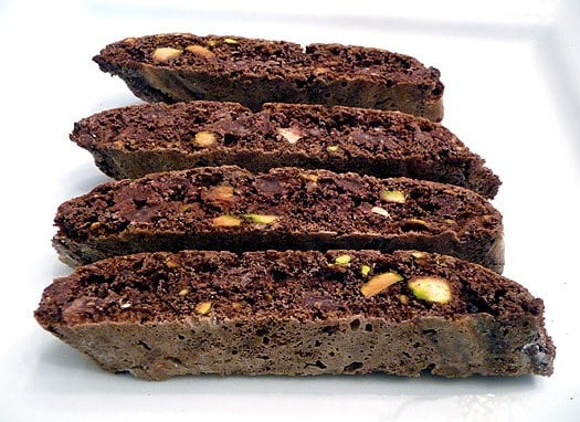 4 pieces of chocolate pistachio biscotti on a white plate.
