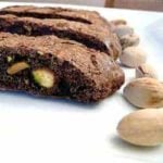 3 slices of chocolate pistachio biscotti on a white plate.