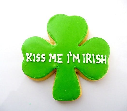Shamrock sugar cookie with green icing and white lettering that says kiss me I'm Irish.