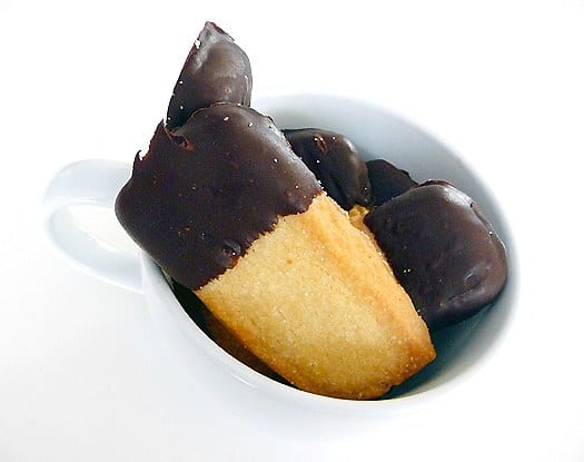 Shortbread cookies with half of each dipped in chocolate in a white mug.