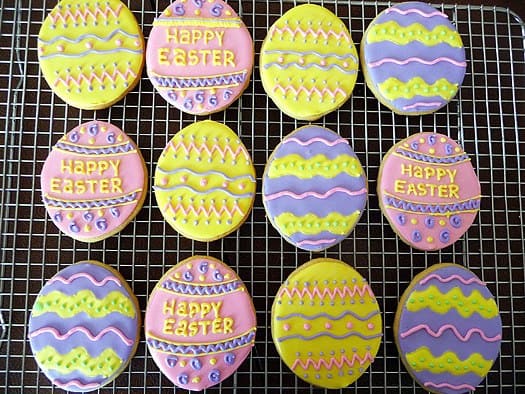 Sugar cookies decorated like Easter eggs on a cooling rack.