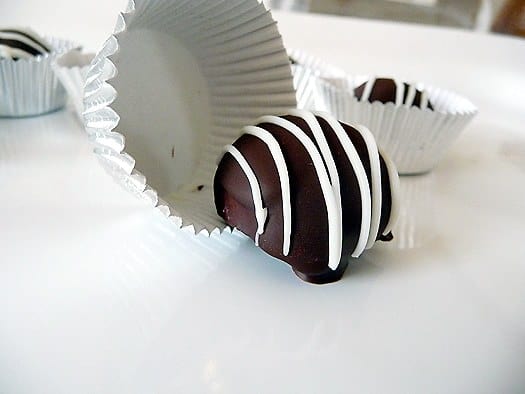 Dark chocolate truffles on a white plate.