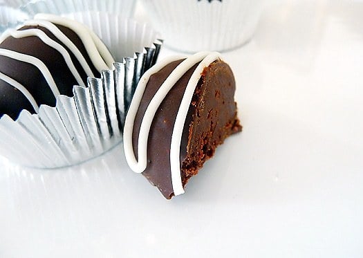 Dark chocolate truffle cut in half on a white plate.