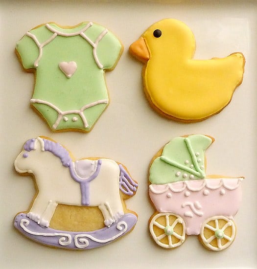 Sugar cookies decorated like a onesie, rubber duck, rocking horse, and stroller for a baby shower.