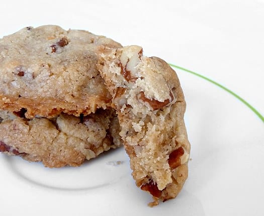 3 pecan sandies cookies on a white plate with one broken in half showing the texture.
