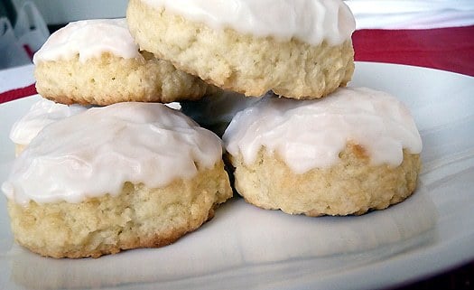 Side view of frosted anise cookies on a white plate.