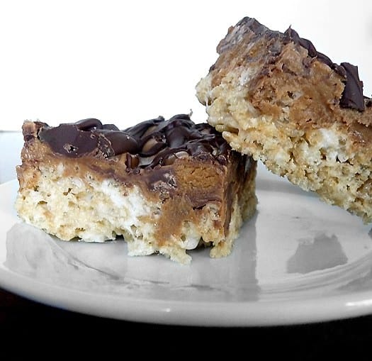 Side view of 2 peanut butter cup Rice Krispies treats on a white plate.