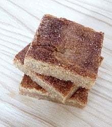 Overhead image of a stack of 3 snickerdoodle blondies on a wood surface.