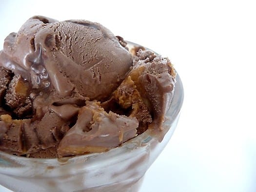 Scoops of chocolate fudge swirl peanut butter ice cream in a glass.