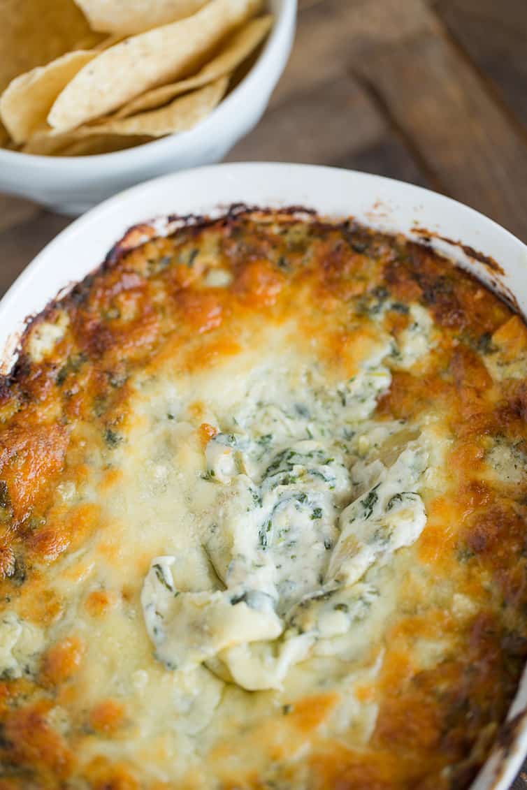 A pan of spinach artichoke dip with some eaten.