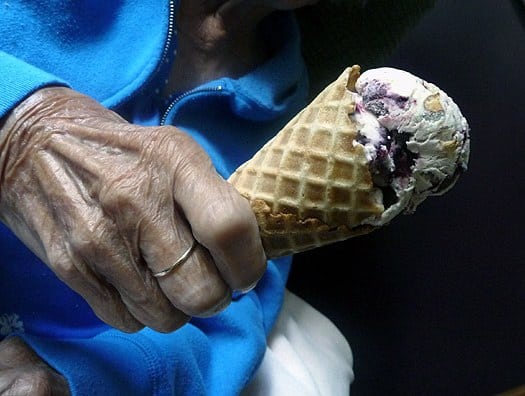 Grandmother holding an ice cream cone topped with toasted almond and candied cherry ice cream.