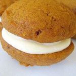 Pumpkin whoopie pie with maple cream cheese filling on a white plate.