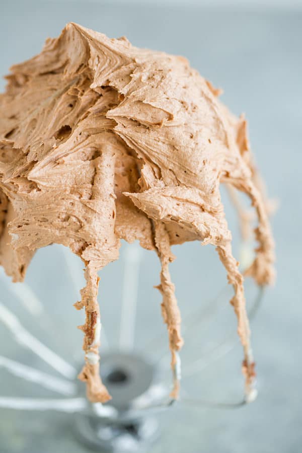 Stand mixer whisk attachment with a ton of chocolate frosting.