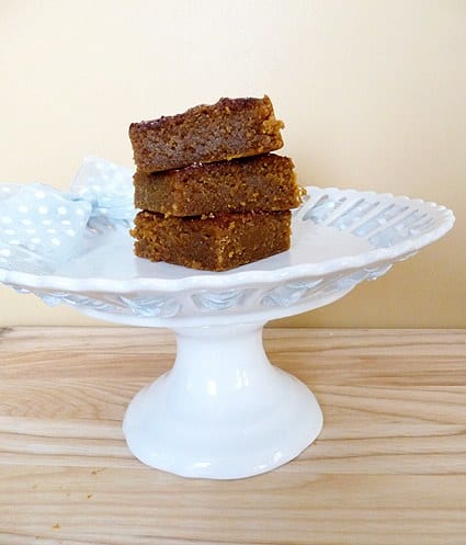Stack of 3 pumpkin pie bars on a white dessert stand.