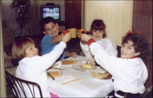 Vintage photo of kids cheers-ing with glasses at a Thanksgiving table.
