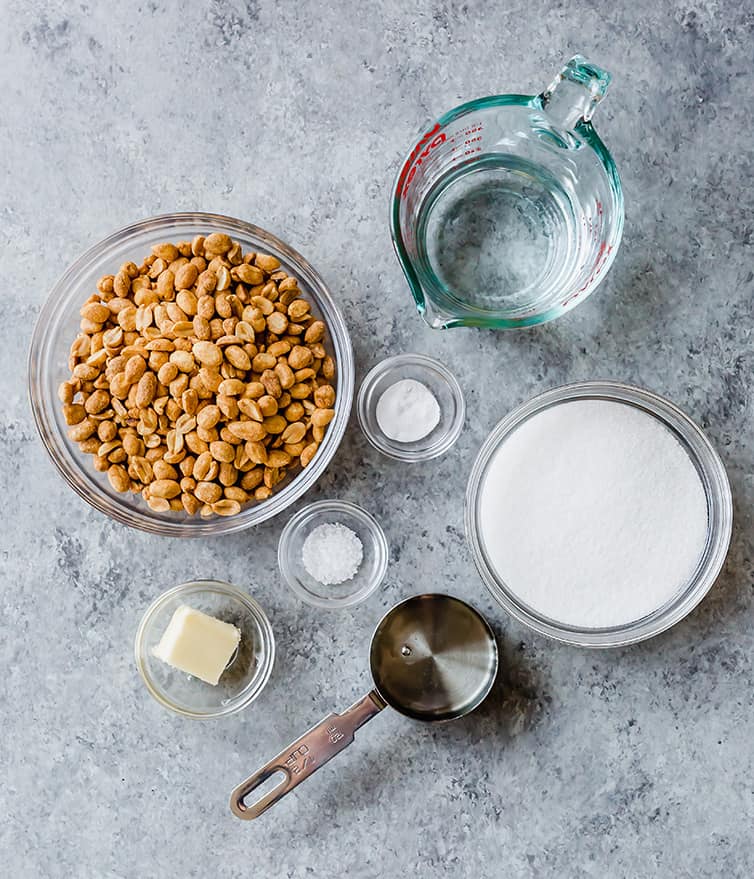 All of the ingredients for peanut brittle measured out - peanuts, water, sugar, corn syrup, salt, baking soda, and butter.
