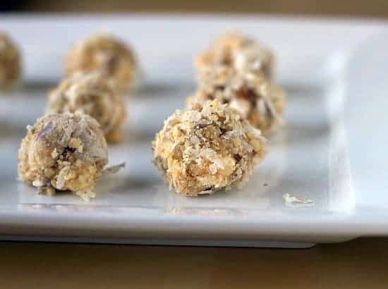 Date, coconut, and walnut truffles on a ceramic serving tray.