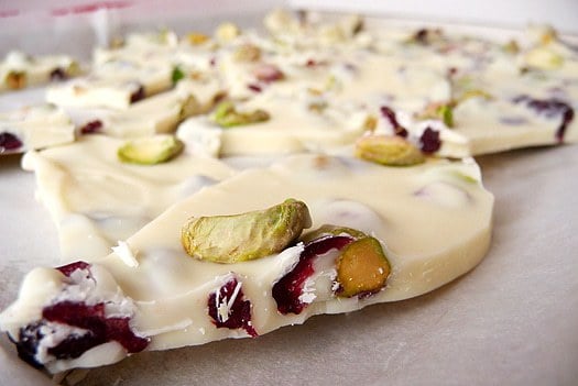 Pistachio and cranberry white chocolate bark on a parchment lined baking sheet before breaking into pieces.