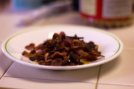 Cooked bacon strips with maple syrup on a white plate.