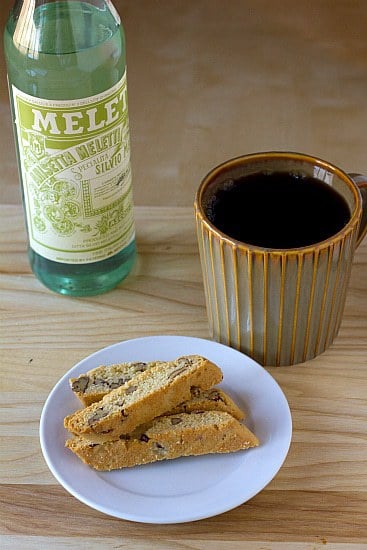 4 pieces of anisette biscotti on a white plate with a cup of coffee.