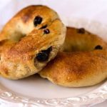 2 blueberry bagels on a white plate.