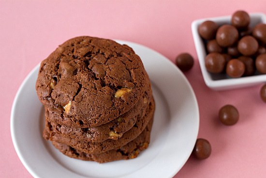 Overhead image of 4 chocolate malted whopper cookies on a white plate.