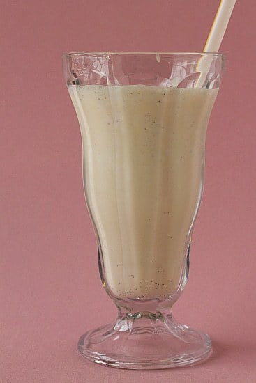 Malted vanilla milkshake in a glass with a straw.