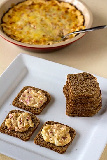 Hot reuben dip spread onto crackers on a white serving tray.