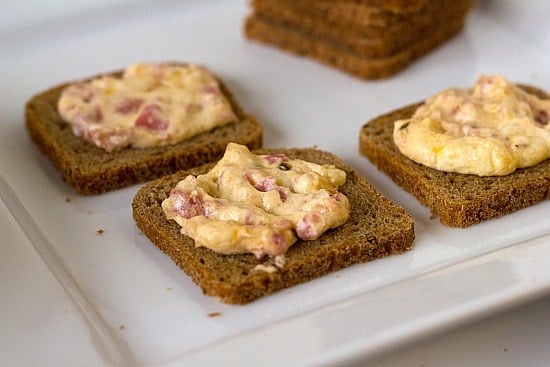 Hot reuben dip spread onto crackers on a white serving tray.