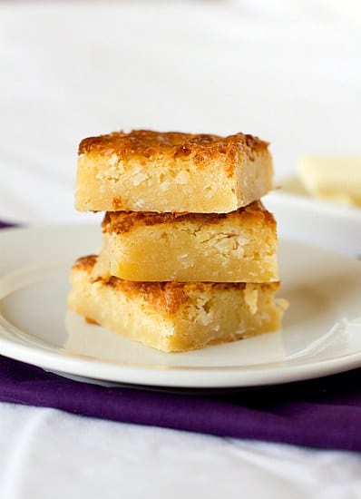 Stack of 3 white chocolate coconut brownies on a white plate.