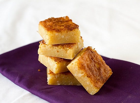 Stack of white chocolate coconut brownies on a purple napkin.