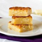 Stack of 3 white chocolate coconut brownies on a white plate.