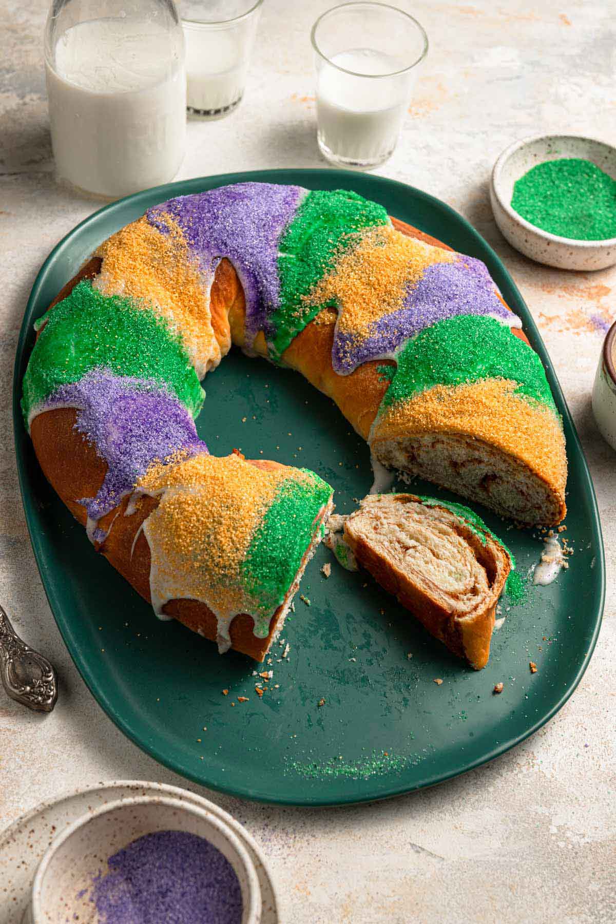 King cake on a platter with a number of slices removed and one on the platter on its side.