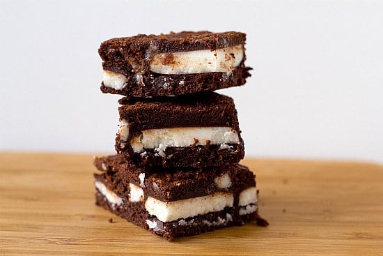 Stack of 3 chocolate mint brownies on a wood surface.