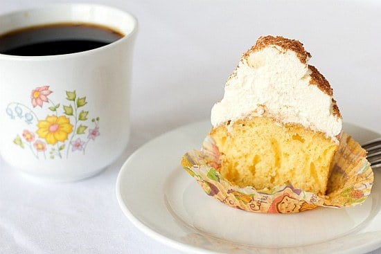 A tiramisu cupcake cut in half on a white plate showing the inside texture.