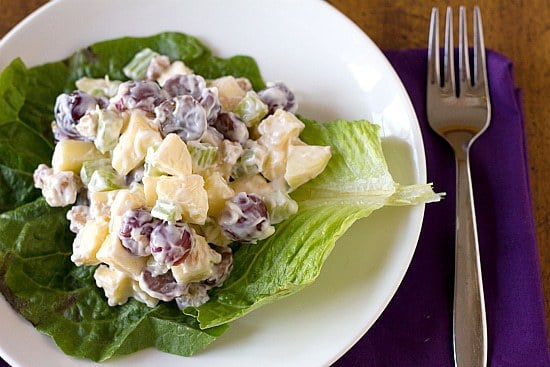 A serving of Waldorf salad on lettuce on a white plate.