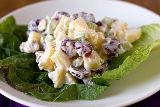 A serving of Waldorf salad on lettuce on a white plate.