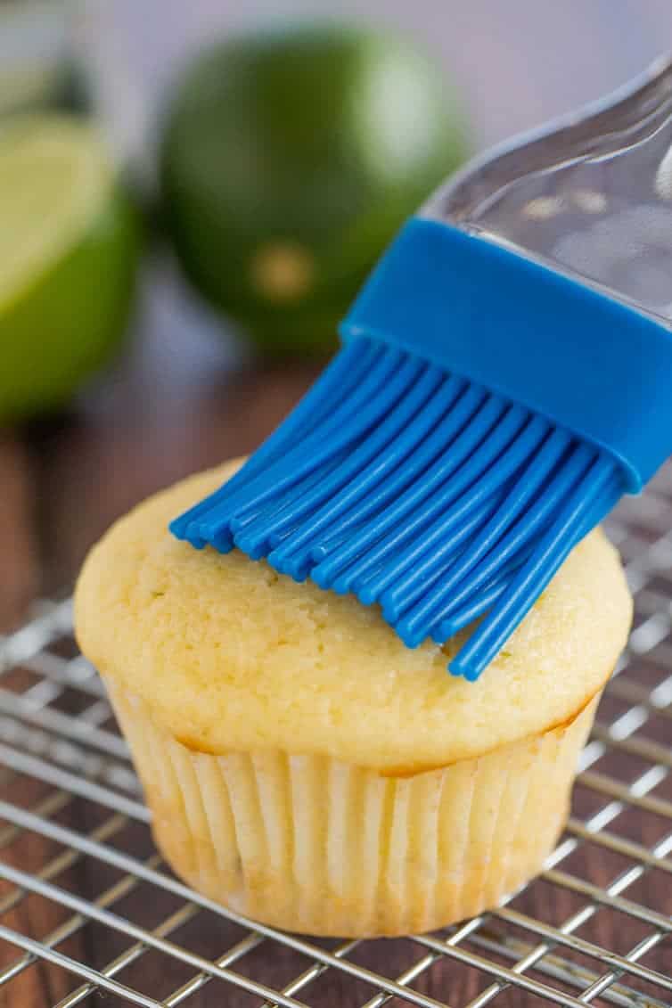 Margarita cupcakes prep: A vanilla cupcake is having tequila brushed on top with a pastry brush.