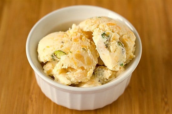 Scoops of dried apricot pistachio ice cream in a white bowl.